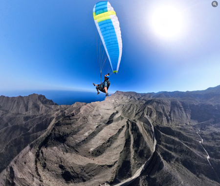 Ole Dalen paragliding over the mountainous landscape of Tirma, Gran Canaria. The clear sky and perfect wind accompany his flight, as he enjoys the panoramic view of the mountains and valley below.